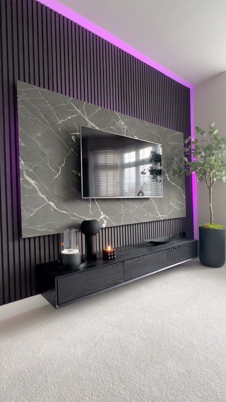 Black low-profile TV unit with a marble backdrop and purple LED wall lighting.