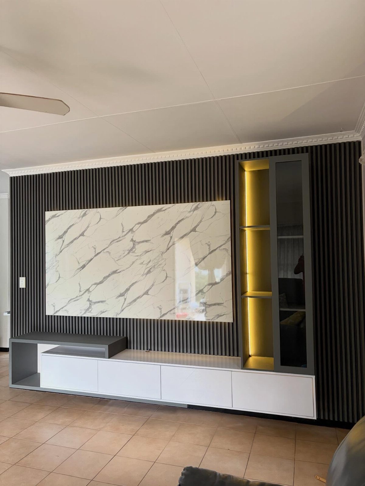 21 Living Room TV Unit Designs Luxury Homes Need in 2026 21 Modern luxury TV unit with slatted wall, marble panel, and illuminated glass cabinet.